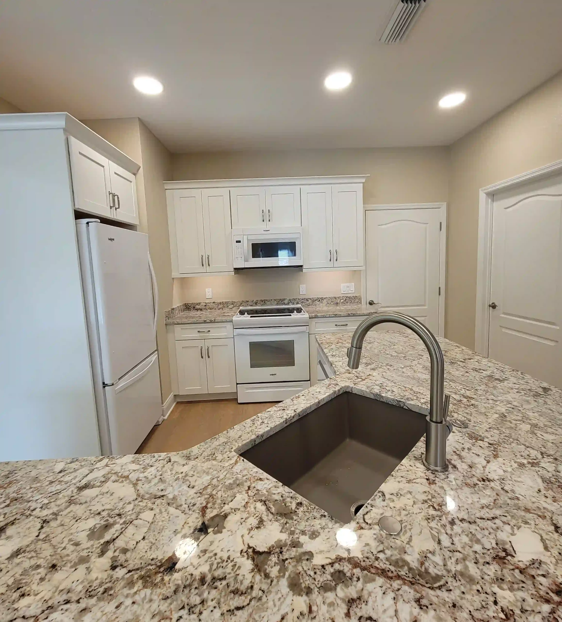 Modern kitchen with granite countertops and white cabinets.