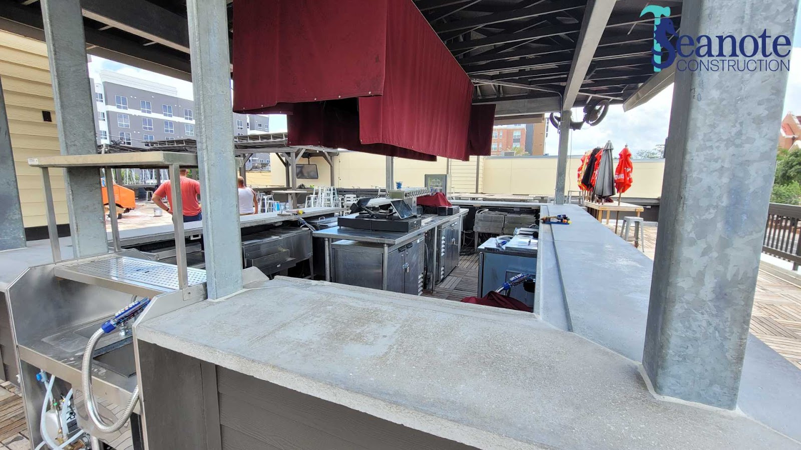 Outdoor kitchen construction with red canopy and appliances.