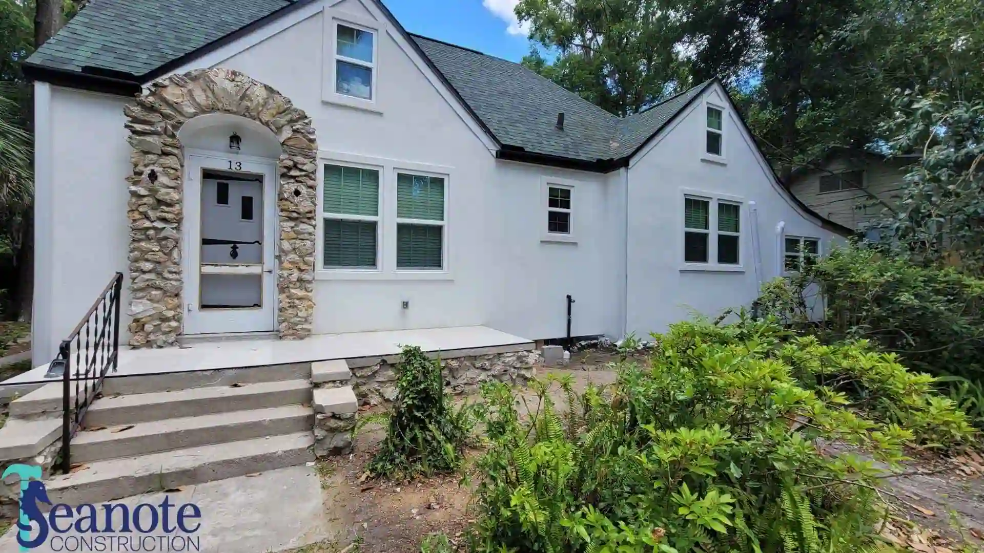 White house with stone arch and greenery
