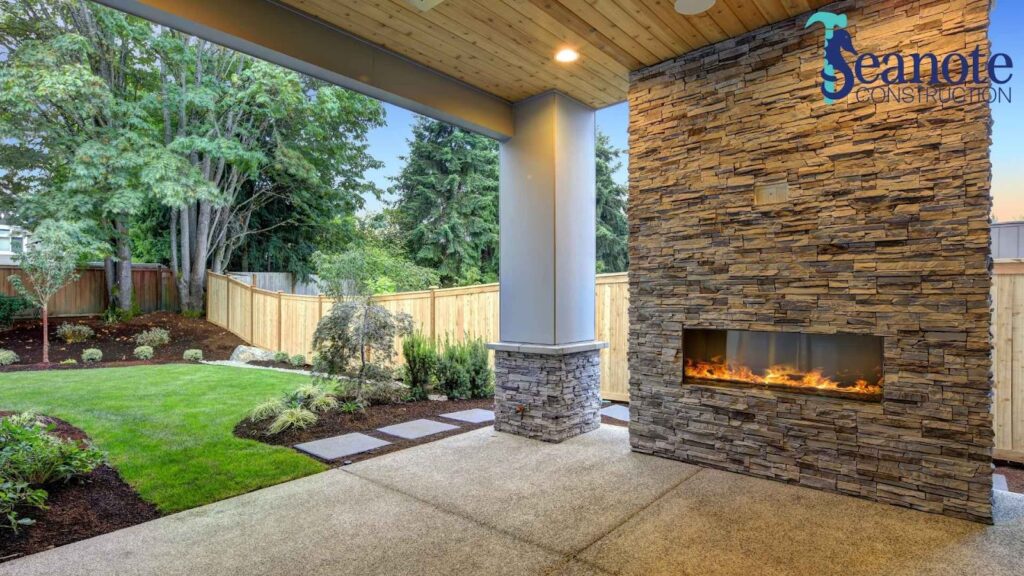 Covered patio with fireplace and landscaped backyard.