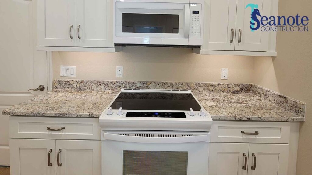 Modern kitchen with granite countertops and white cabinets.