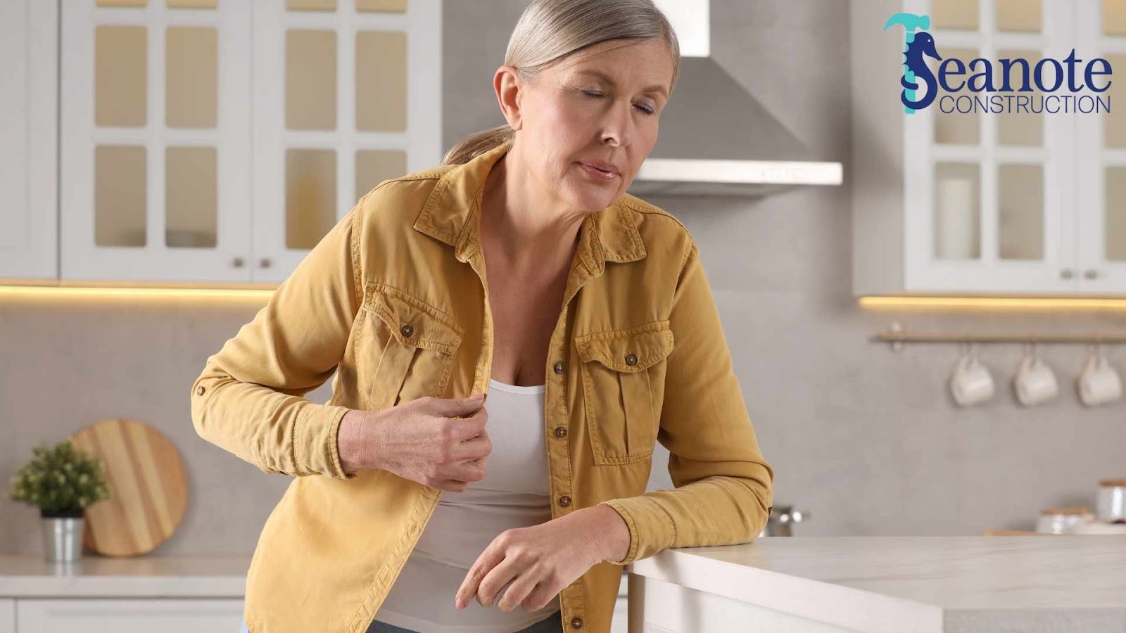 Old woman in kitchen clutching chest, looking unwell