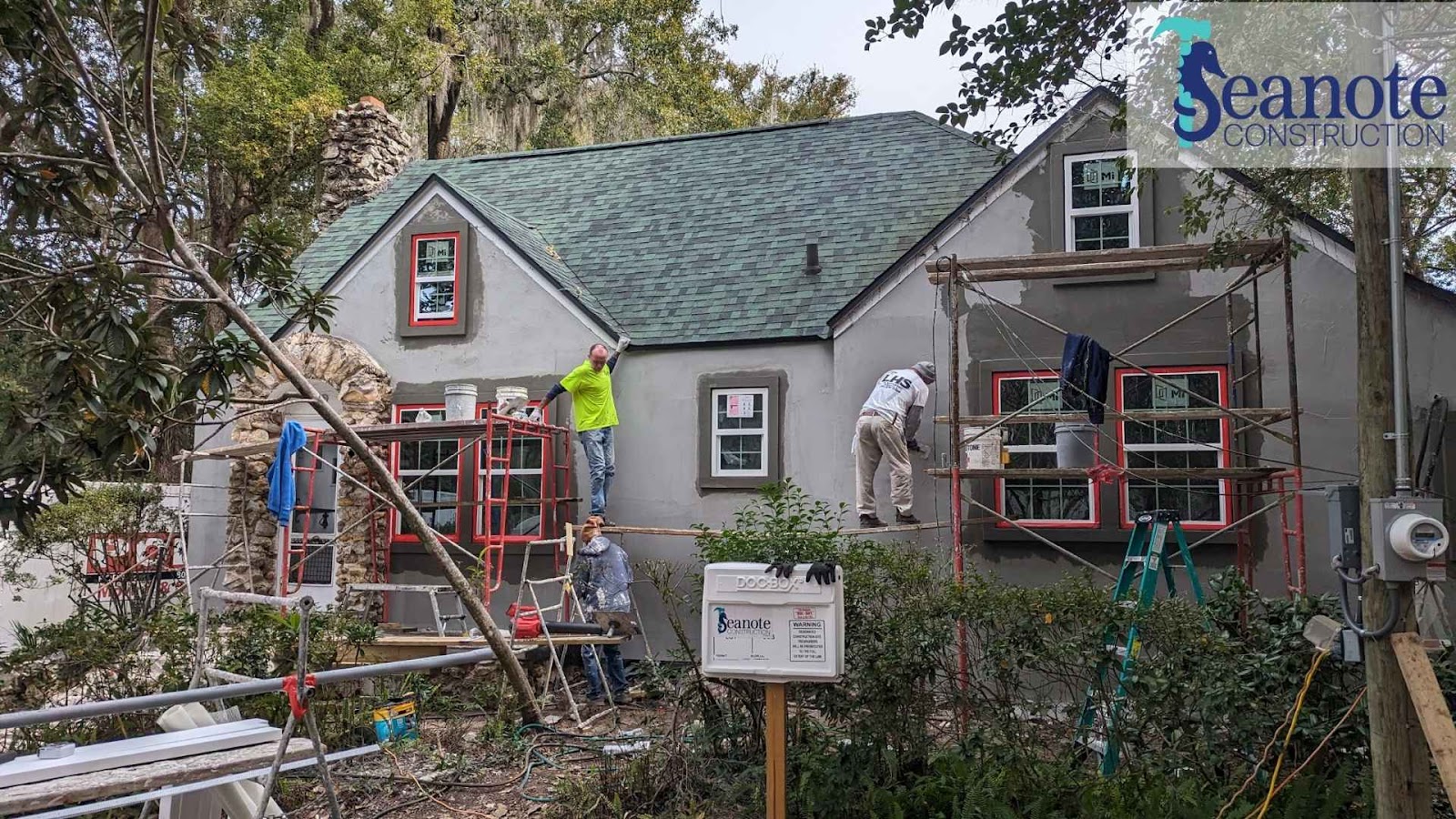 Workers renovating house exterior with scaffolding