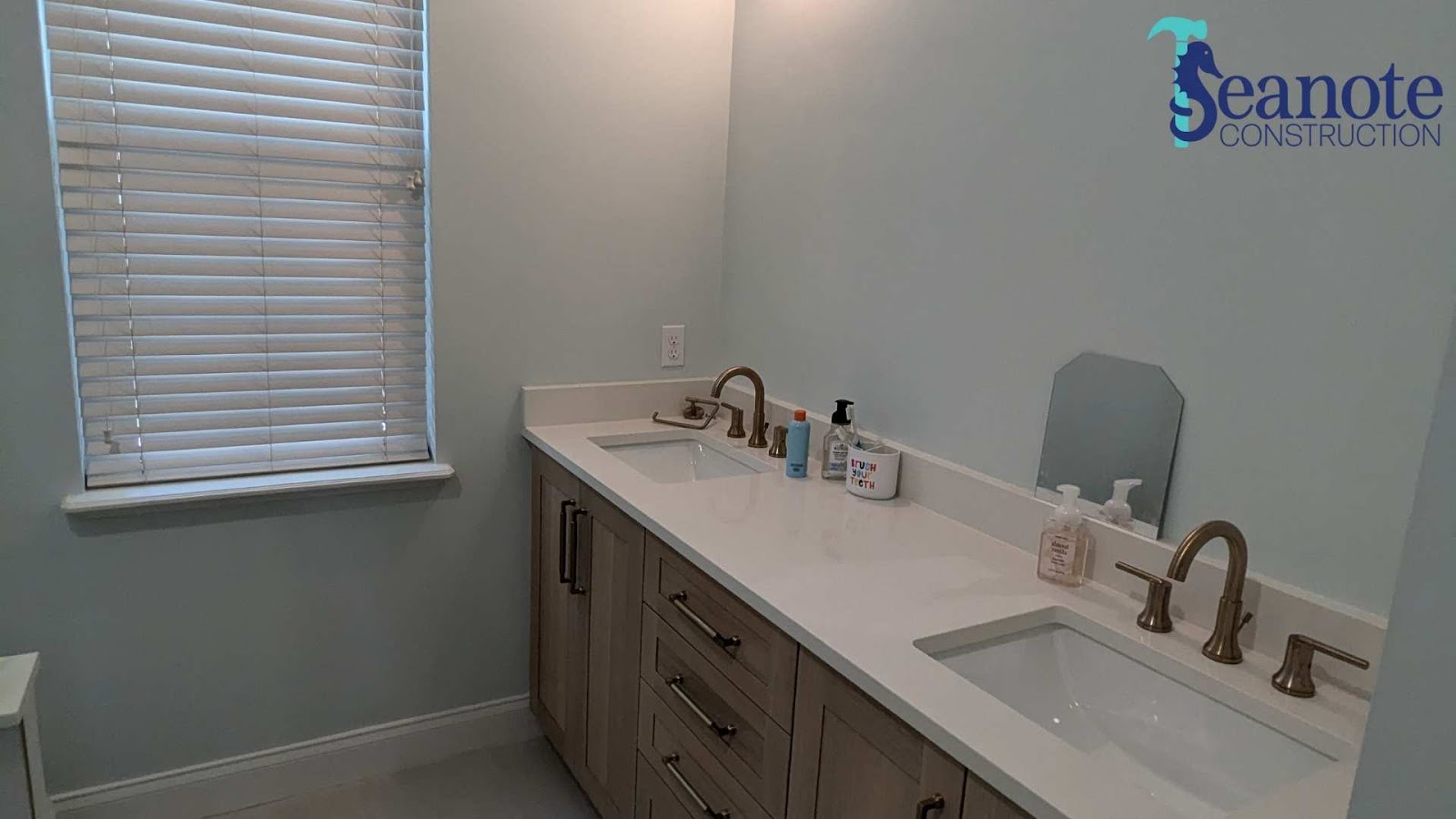 Quarter bathroom with double sinks and window blinds.