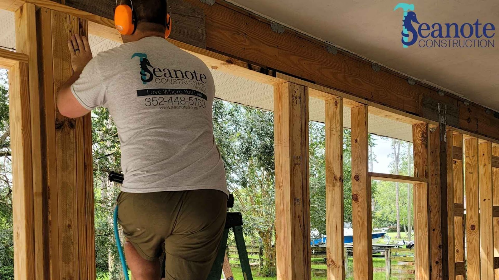 Seanote construction worker measuring wooden frame indoors.