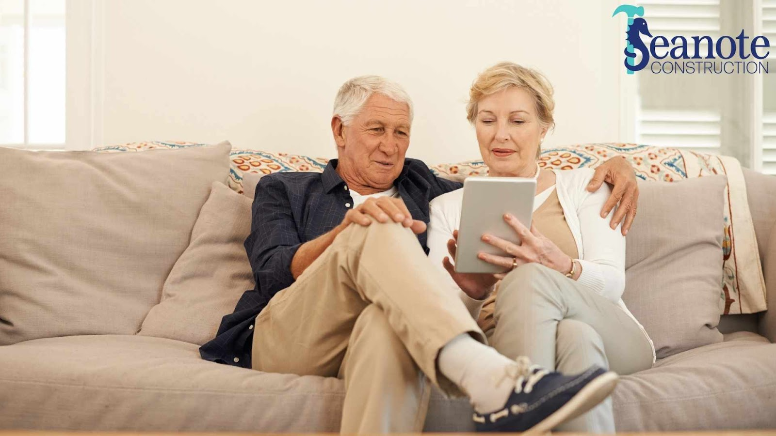 Older couple using tablet on couch, Seano Construction.
