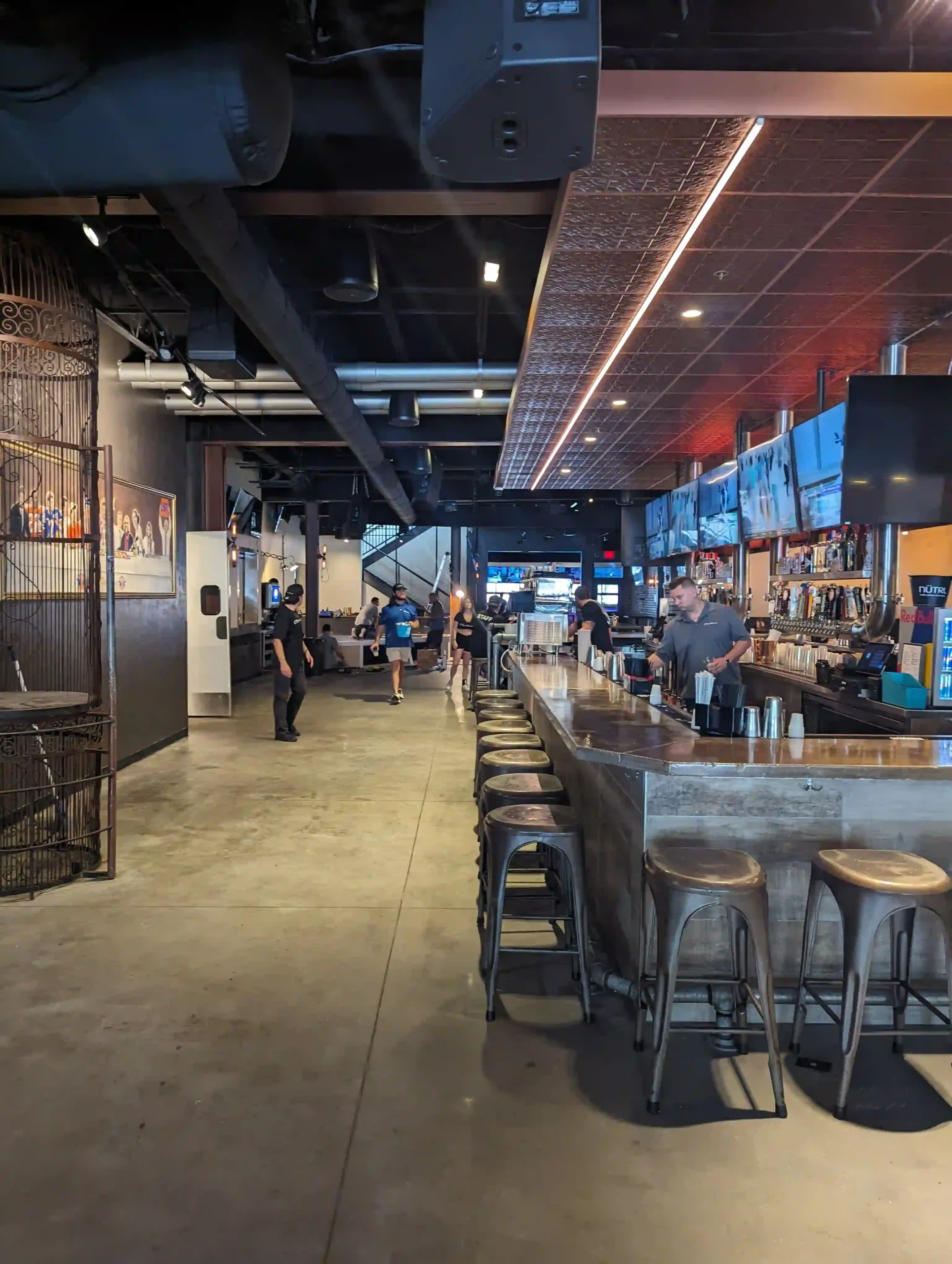 Modern bar interior with stools and televisions.