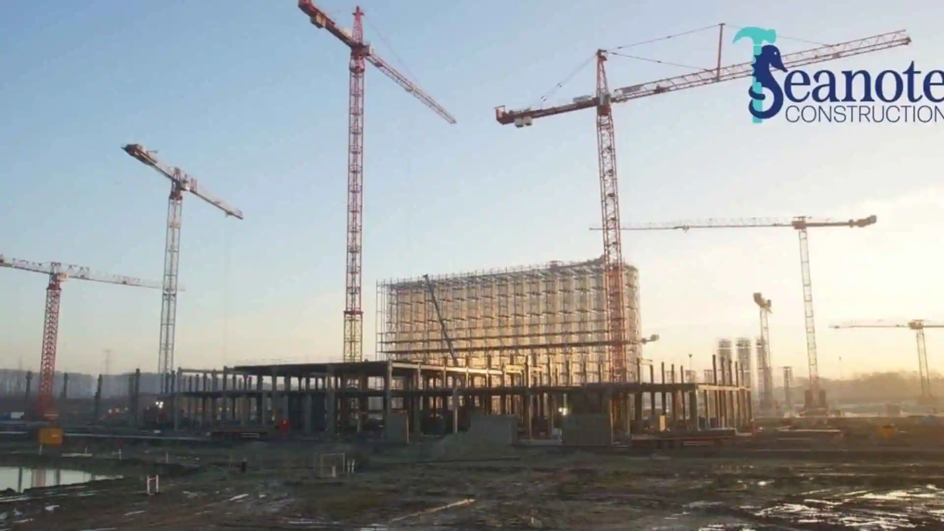 Tower cranes surround a large building under construction.